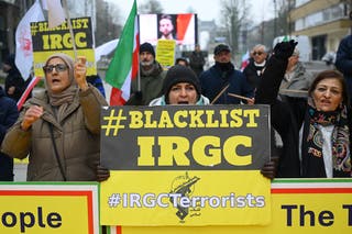 Apoiantes do Conselho Nacional de Resistência do Irão agitam bandeiras iranianas e seguram cartazes